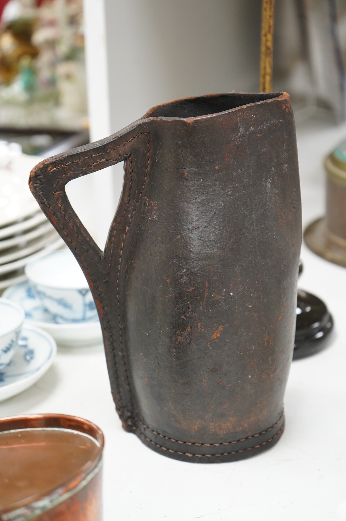 An adjustable wig stand, an oval copper box and a leather black jack jug, 24cm high.